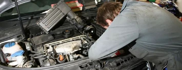 Technician in grey hoodie looking at engine